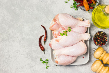 Raw chicken legs, drumsticks on concrete background. Top view, space for text.