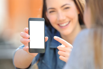 Woman showing a blank smart phone screen to a friend