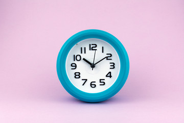 Blue and white alarm clock on pink background.