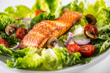 Roasted salmon fillet with fresh vegetable salad on white plate