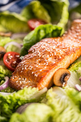 Roasted salmon fillet with fresh vegetable salad tomatoes mushrooms and sesame