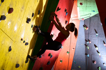 Young Active Woman Bouldering on Colorful Artificial Rock in Climbing Gym. Extreme Sport and Indoor...