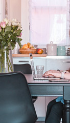A girl with a notebook and computer sits at the table and takes notes. Work at home and freelance. Cozy home. Business lady at home. Free space for text.