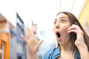 Surprised woman receiving good news talking on phone