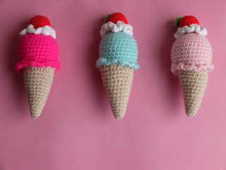 Knitted multicolored ice cream toys against pink background