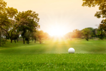 White Golf ball on green course to be shot on blurred beautiful landscape of golf course in bright...