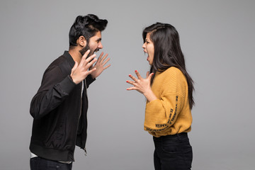 Angry indian couple shouting at each other quarrel on gray background