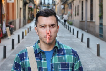 Uncomfortable man blocking his nose with clothespin 