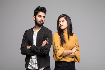 Beautiful indian couple standing apart from each other while being in a quarrel isolated on grey background.