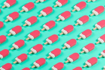 Isometric pattern made of pink glossy lolly ice cream on the green table.