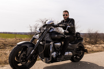  Handsome man on a black classic motorcycle