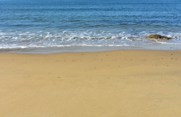 Fototapeta na wymiar Beach with golden sand and blue sea with foam.