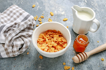 Healthy breakfast: bowl of cornflakes on grey, stone background.