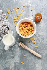 Healthy breakfast: bowl of cornflakes on grey, stone background.