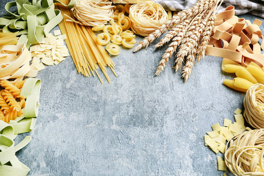 Mixed types and shapes of italian pasta on grey stone, background