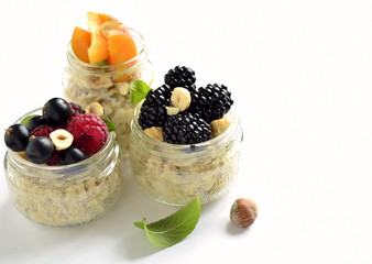 Oat flakes with various berries, hazelnuts and honey in glass jars,  copy space