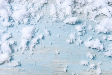 Real, natural snow on blue wooden background.