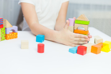 Schoolgirl girl play with educational toy on table in the children's room. Two kids playing with colorful blocks. Kindergarten educational games