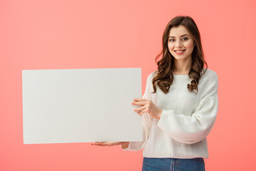 Fototapeta na wymiar smiling and beautiful woman holding blank placard with copy space isolated on pink