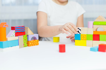 Schoolgirl girl play with educational toy on table in the children's room. Two kids playing with colorful blocks. Kindergarten educational games