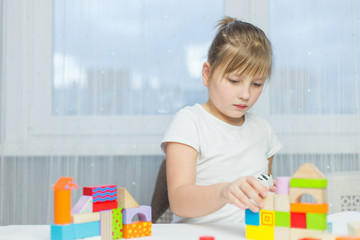 Schoolgirl girl play with educational toy on table in the children's room. Two kids playing with colorful blocks. Kindergarten educational games