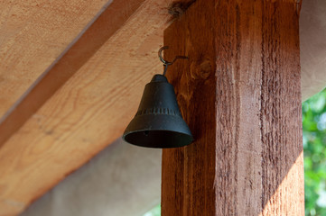 Souvenir bell hanging from the iron hook mounted to the crude oiled wooden beam