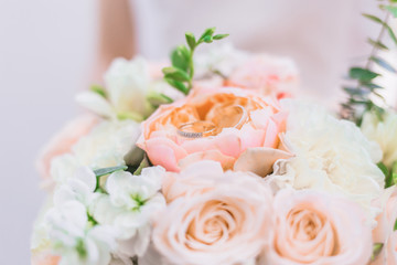 The bride is holding a wedding bouquet in pastel colors of peonies and roses
