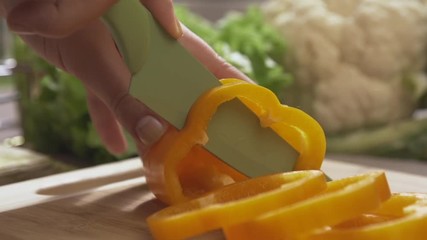 Chief cutting yellow peppers on a wooden board with a professional knife and a great skill. Scene. Close-up of chief making salad healthy food and chopping bell pepper on cutting board