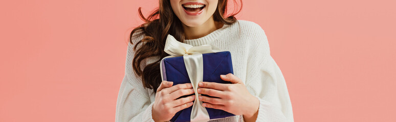 cropped view of woman in white sweater holding gift box isolated on pink