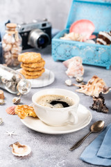 Cup of coffee and biscuits with seashells and decorations. Dreams of sea vacation and concept
