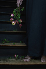 dead roses and woman in black linen dress as symbol for divorce or a weeping widow