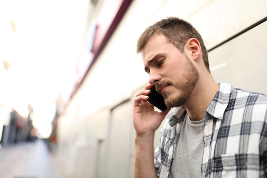 Sad man talking on phone in the street