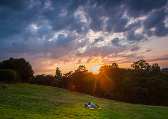 Para na kocu, piknik podczas zachodu słońca na tle chmur i lasu