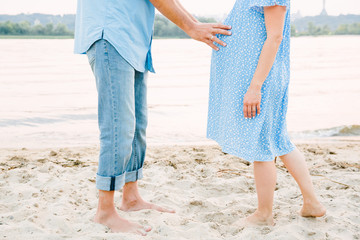 young pregnant couple holding hands on the beach