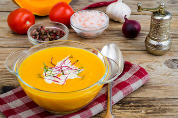 Orange delicious vegetable cream soup on wooden table.