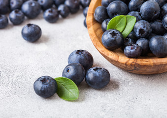 Fresh raw organic blueberries with leaf in wooden bowl on white background. Macro