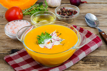 Orange delicious vegetable cream soup on wooden table.