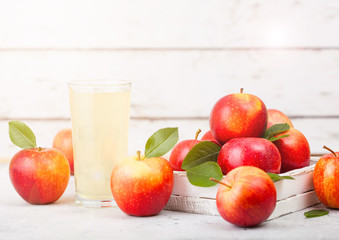 Glass of fresh organic apple juice with braeburn pink lady apples in box on wooden background with sun light