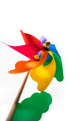 A Catherine wheel wind (pinwheel) isolated on white background. Colors: green, yellow, blue, purple, fuchsia, orange, red. Child's toy made of plastic curls attached to a wooden stick. Like a flower.