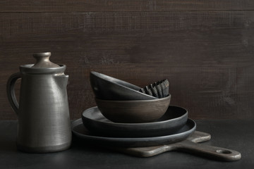 Crockery, clayware, dark utensils and stuff on dark tabletop. Kitchen still life.