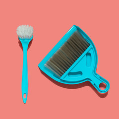 A pale blue dustpan, brush and brush for dish washing lying on living coral background. In the style of pop art. Top view.