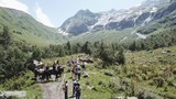 Aerial shooting from flying drone hiking group walking on mountain trail. Tourist group traveling in mountain valley. Hiking tour in mountain. Traveling group walking on mountain trail aerial view