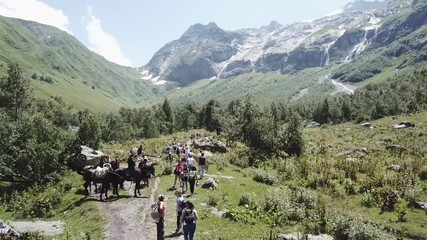 Aerial shooting from flying drone hiking group walking on mountain trail. Tourist group traveling in mountain valley. Hiking tour in mountain. Traveling group walking on mountain trail aerial view