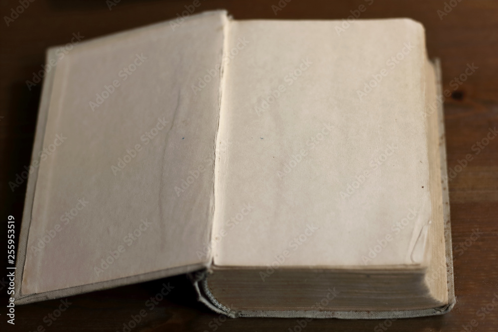 Fototapete An open old retro book with white blank empty pages on which the designer can write a greeting text or a postcard on the wooden background of the library atmosphere