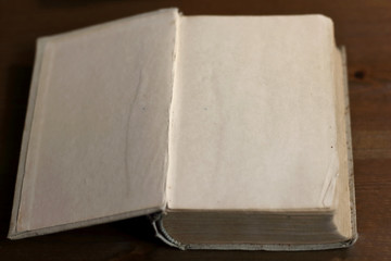 An open old retro book with white blank empty pages on which the designer can write a greeting text or a postcard on the wooden background of the library atmosphere