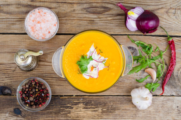Obraz na płótnie Canvas Orange delicious vegetable cream soup on wooden table.