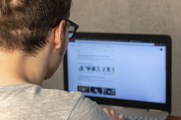 man with glasses working at a laptop at home. soft focus. home work concept