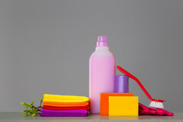 Colorful set of tools for cleaning the house and twigs with green leaves on neutral background. The concept of spring cleaning. Copy space.