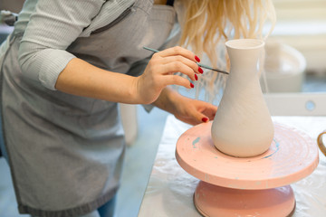 girl paints a clay jug in a pottery workshop