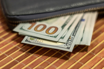 Fan hundred dollar bills in a black wallet